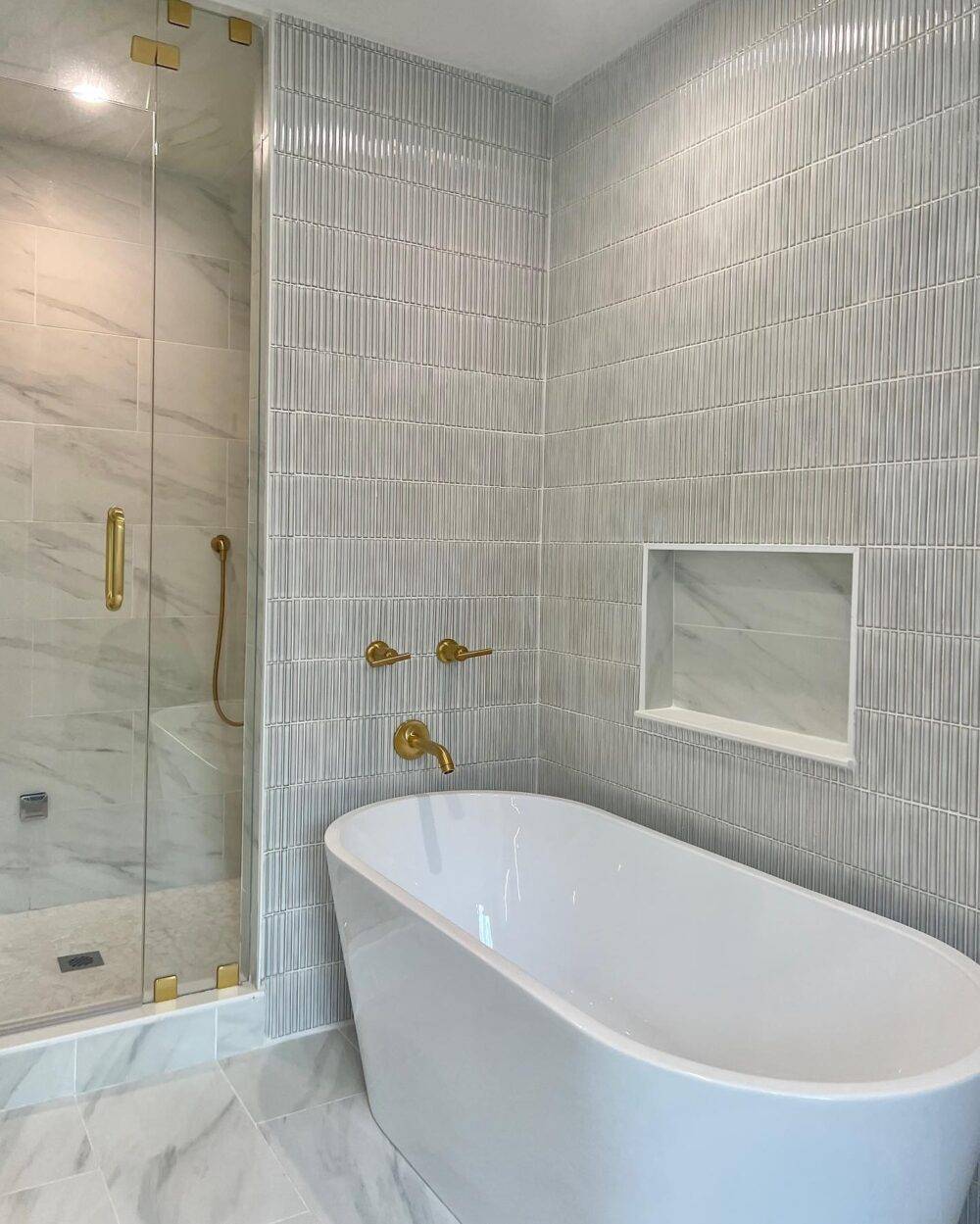 This bathroom features a white and grey mosaic wall tile and white marble with grey and beige viening. 