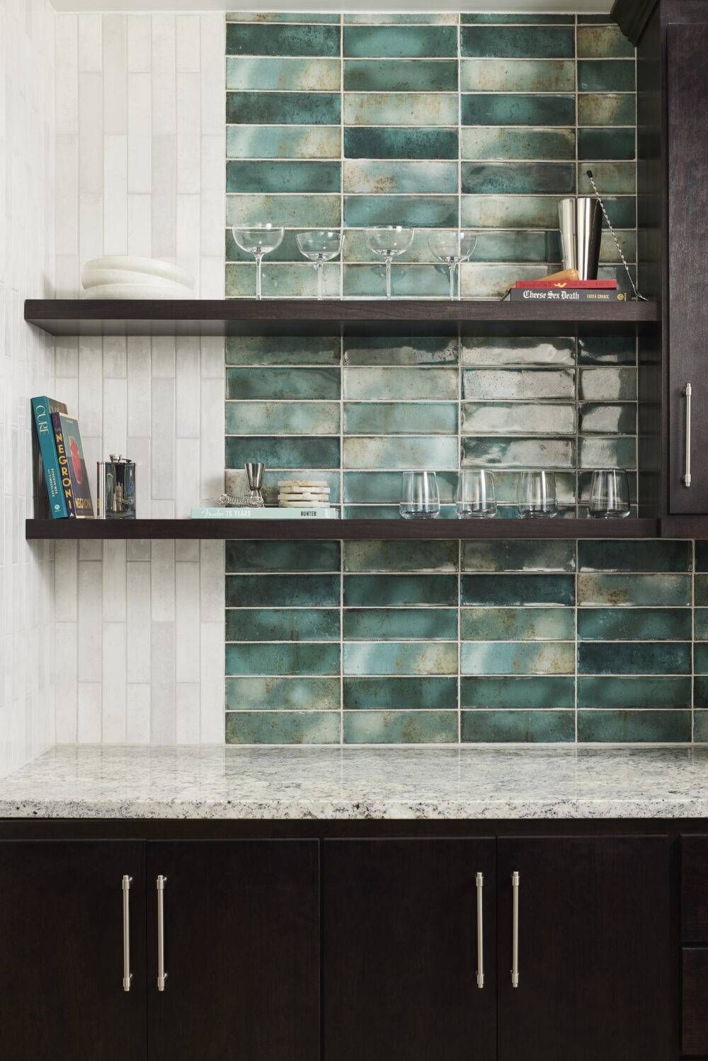 A bar backsplash that features white and green handmade-look subway tile.