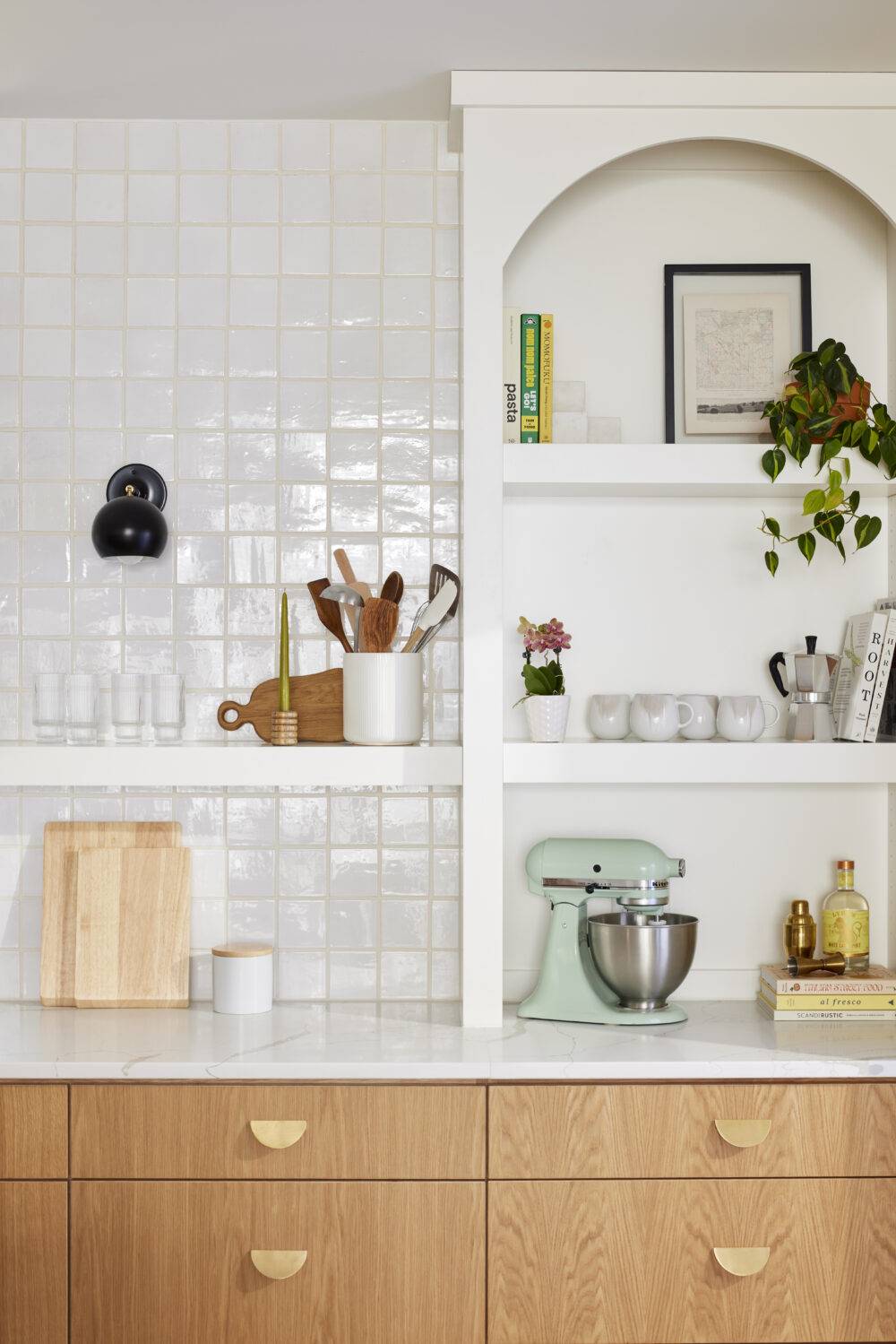 This bright and charming kitchen features white Zellige tile backsplash and open white shelves. 