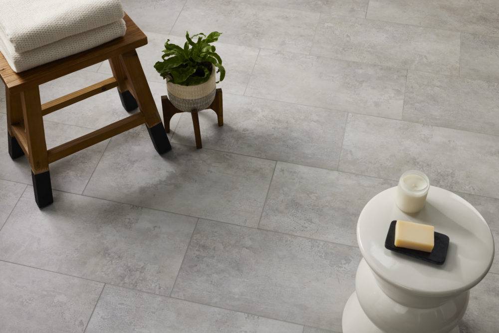 stone look tile floor with wood stool and white side table with candle 