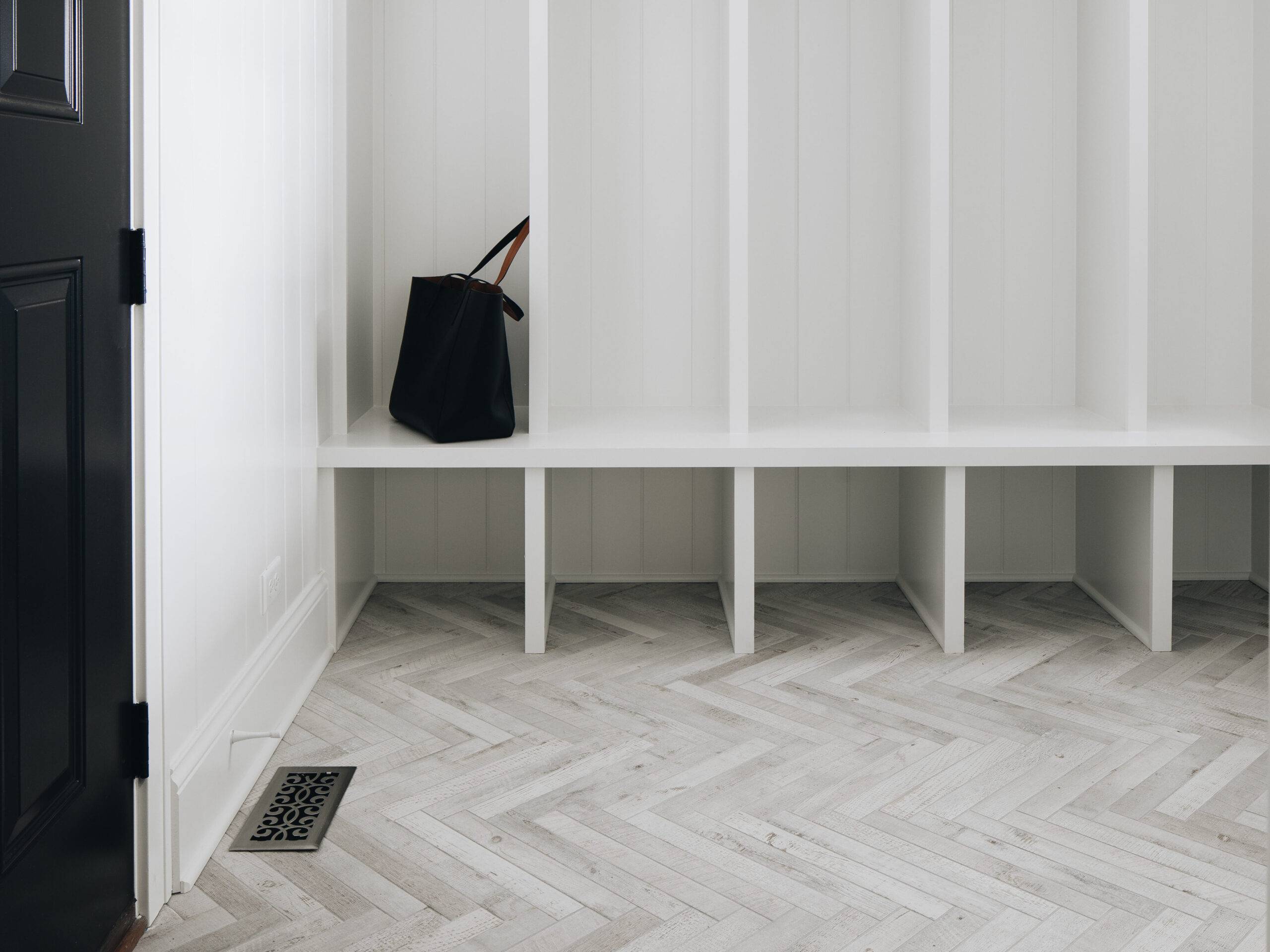 This stylish mudroom features a light-wood look tile floor in a herringbone pattern. 