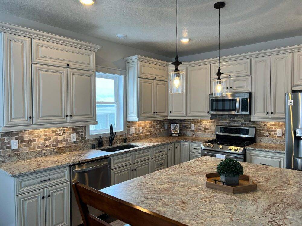 This transitional kitchen features a brown and grey travertine tile backsplash. 